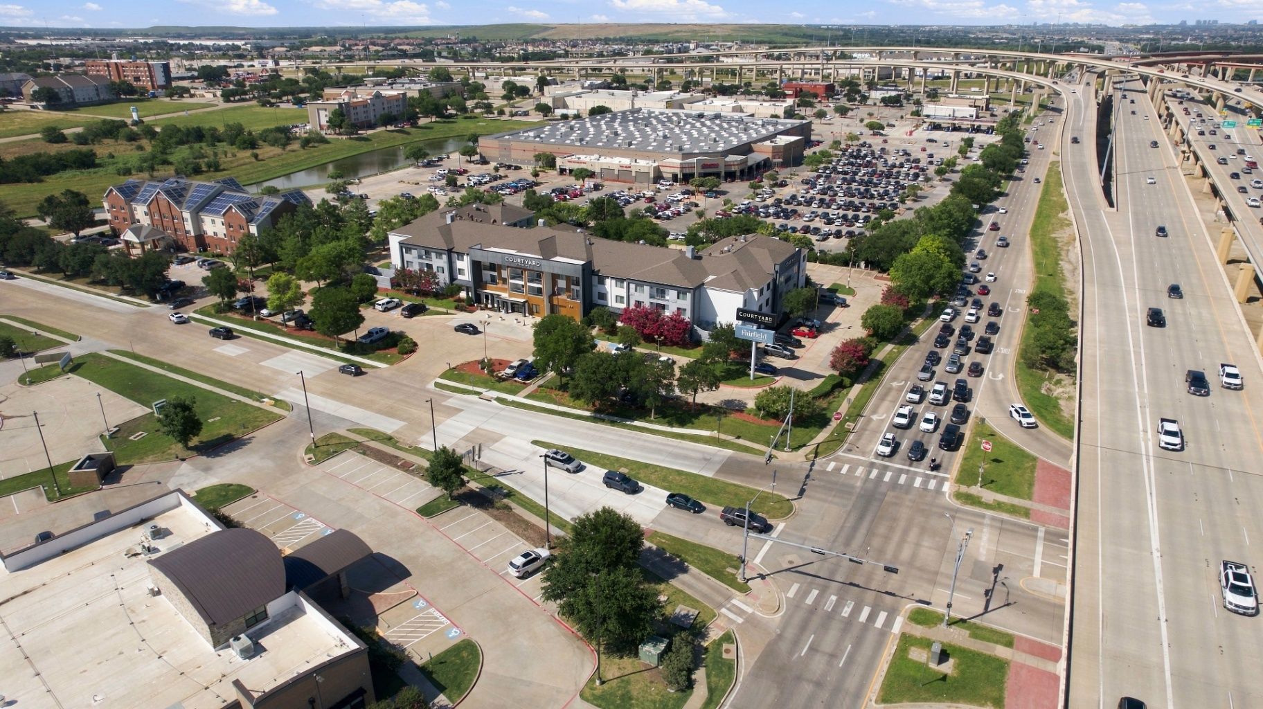 Aerial view of a commercial development, major roadway, parking areas, surrounding properties, and location context
